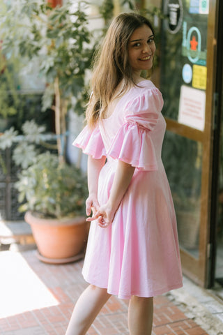 Blossom Dress – angled back view – round scoop back, puff sleeves with flared cuffs, flared skirt, light pink cotton – Cori Tailor