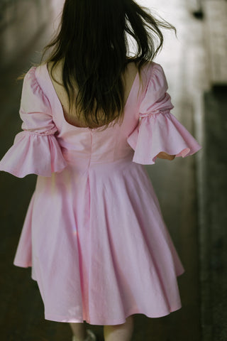 Blossom Dress – back view – round scoop back neckline, puff sleeves with flared cuffs, flared skirt, light pink cotton – Cori Tailor