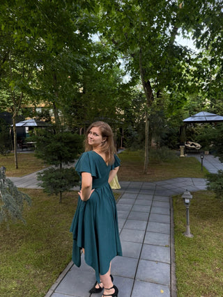 Made-to-measure green cotton dress with handkerchief hem and flutter sleeves – back view worn outdoors, handmade by Corina at Cori Tailor