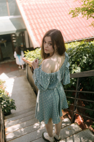 Daisy Dress – back view on stairs – off-shoulder elastic neckline, long sleeves, drawstring waist, flared skirt – Cori Tailor