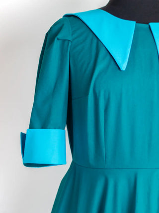 Close-up of the Daphne Dress by Cori Tailor — detailed view of the pointed contrast collar and turned-up sleeve cuff in vibrant turquoise cotton against a deep teal bodice.