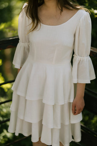 Close-up view of the Freya Dress by Cori Tailor, showcasing the tiered skirt and puff sleeves in lightweight white cotton