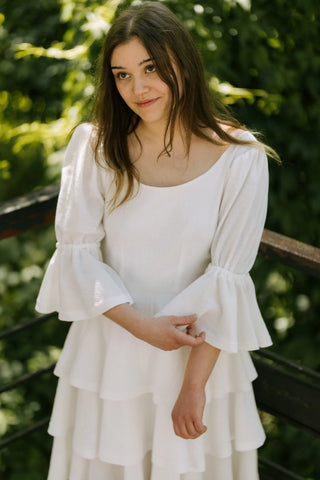Model wearing the Freya Dress by Cori Tailor, with puff sleeves and tiered skirt, photographed outdoors