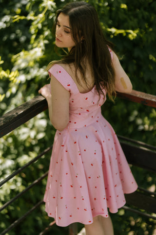 Back view of the Lolita Skirt by Cori Tailor, pink gingham pattern with cherry print, paired with matching crop top, photographed outdoors