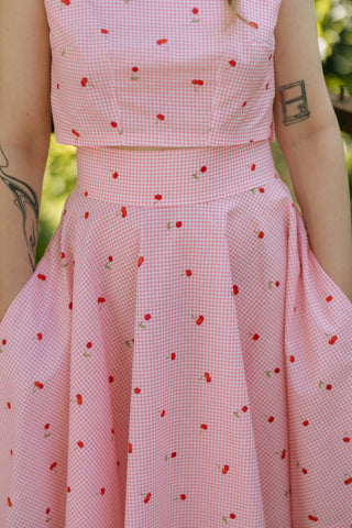 Close-up of the Lolita Skirt by Cori Tailor, showing high waistband and pink gingham fabric with cherry print, paired with matching crop top
