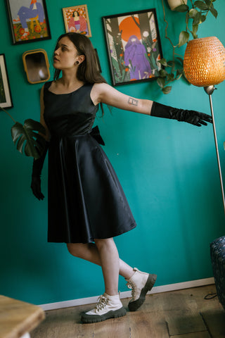Sabrina Dress – front view – sleeveless round neckline, fitted waist with bow at back, flared skirt, black satin fabric – Cori Tailor