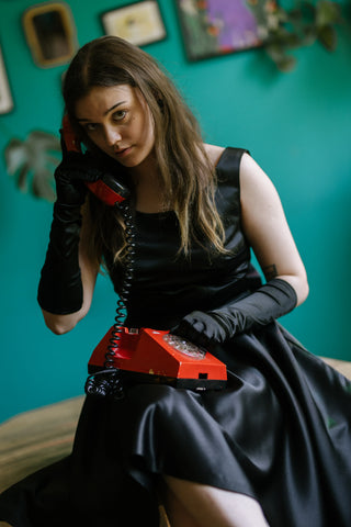 Sabrina Dress – styled close-up view – sleeveless round neckline, fitted bodice, flared taffeta skirt, black gloves, vintage red rotary phone – Cori Tailor