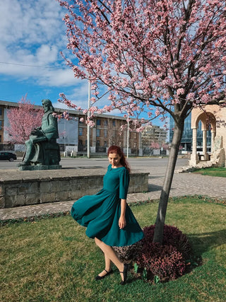 Andreea wearing the Sophia dress by Cori Tailor, twirling gracefully under blooming cherry blossoms in Iași, Romania.